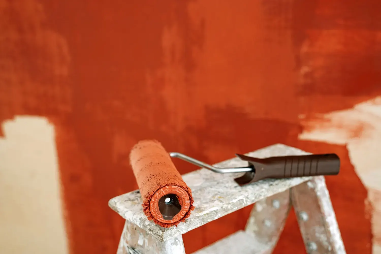 Paint roller resting on a ladder beside a freshly painted wall in a Marietta, GA home