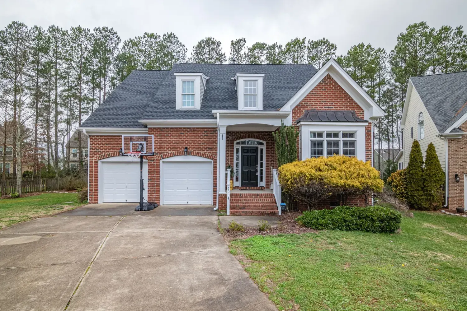 Painter in Kennesaw, GA: brick-front home with a two-car garage among tall pines